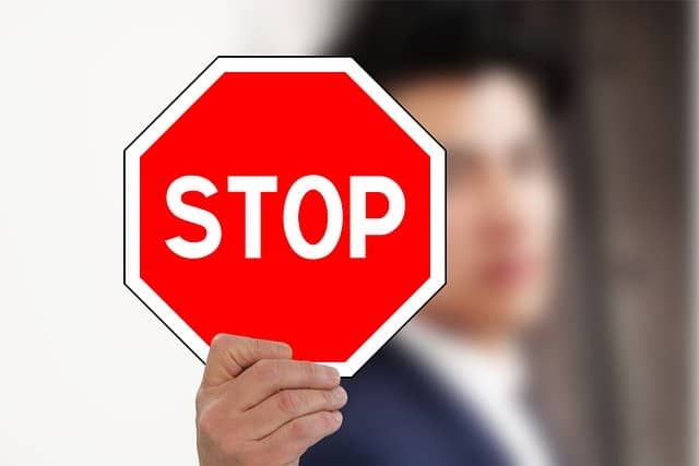 stop buying stuff. man holding up a stop sign